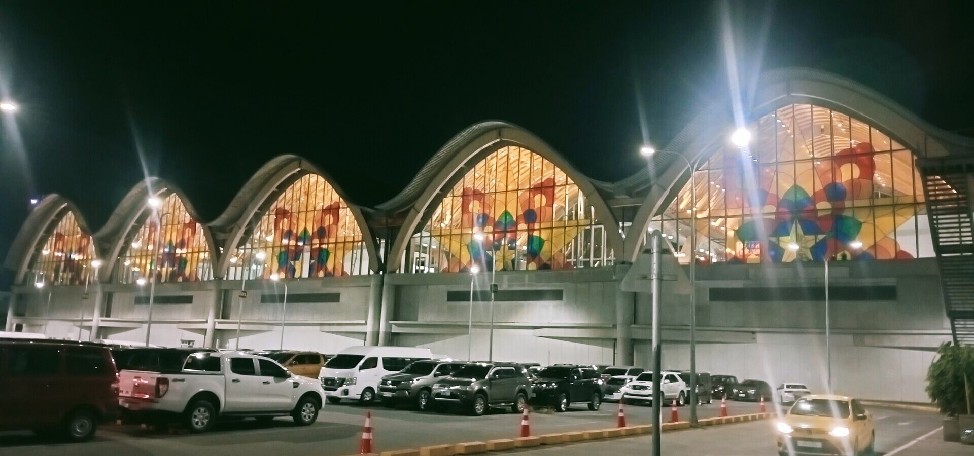 Terminal 2 of Mactan-Cebu International Airport at night, with its curved roof and colourful glass
