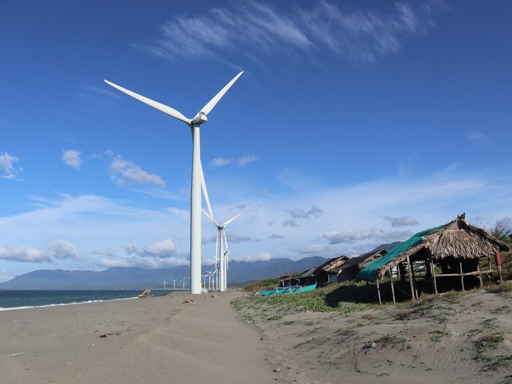 Nipa-hut souvenir stalls on the black-sand beach below the turbines