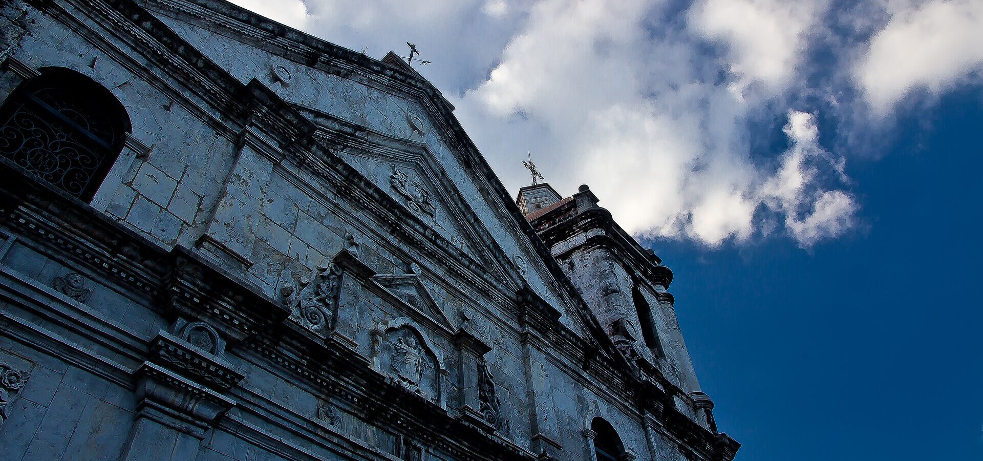 The basilica's stone front and bell tower seen from below against a blue sky