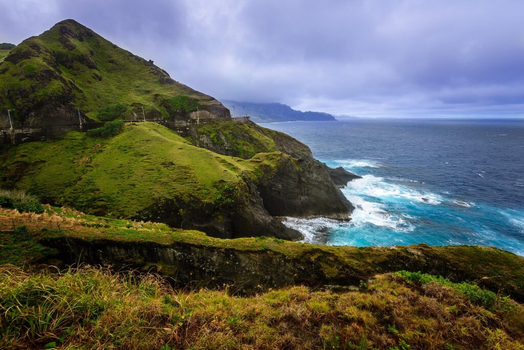 Green cliffs dropping to white surf on Batan's rugged coast