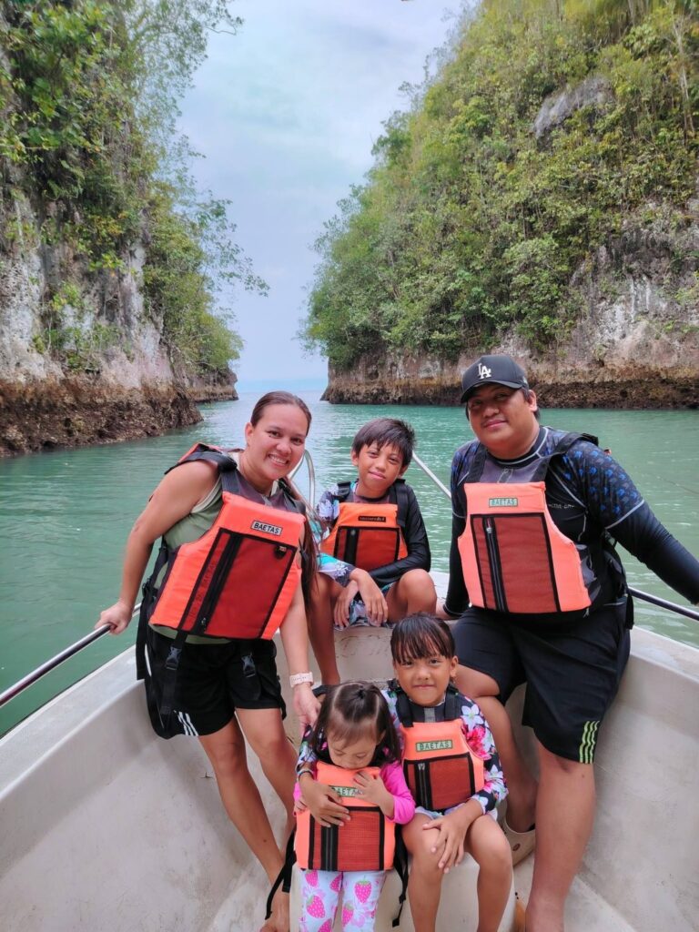 A family in orange life vests on the tour boat between the cliffs