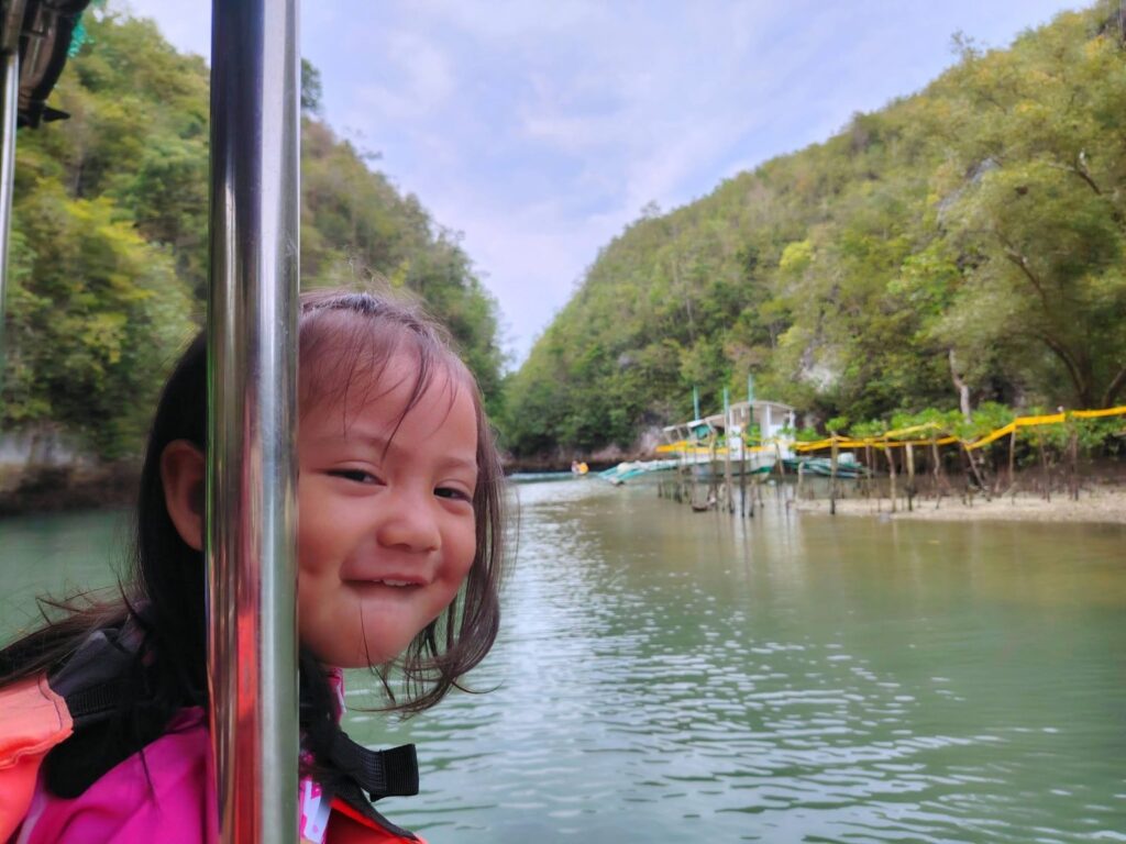 A smiling child on the tour boat with the river and green hills behind