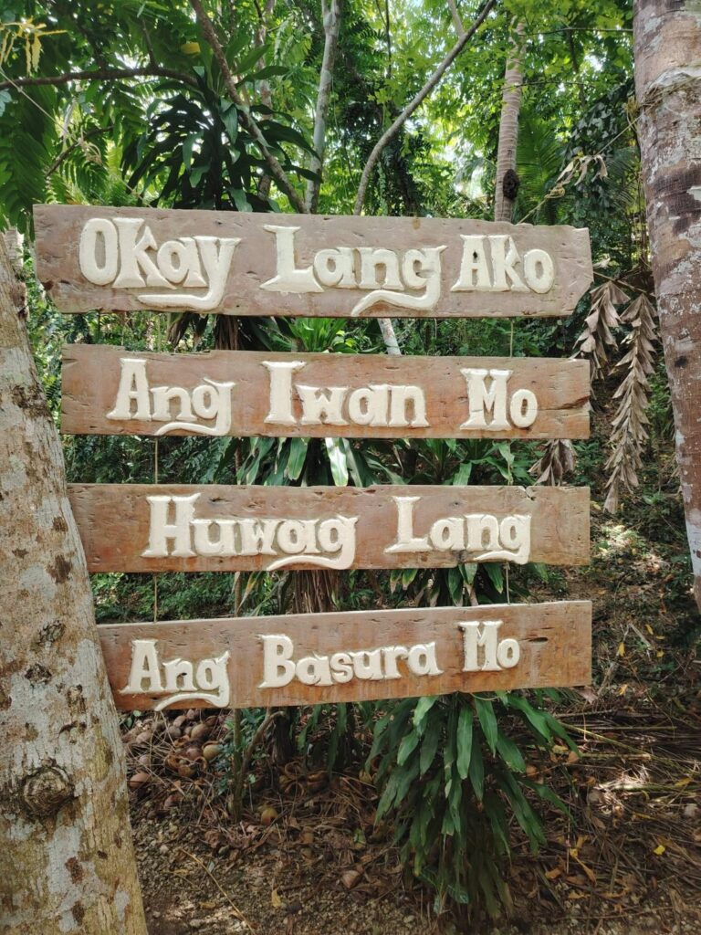 Hand-painted wooden signs in Cebuano asking visitors not to leave rubbish