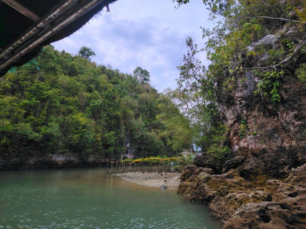 Limestone cliffs and a small sandy shore at the mouth of the Bojo River