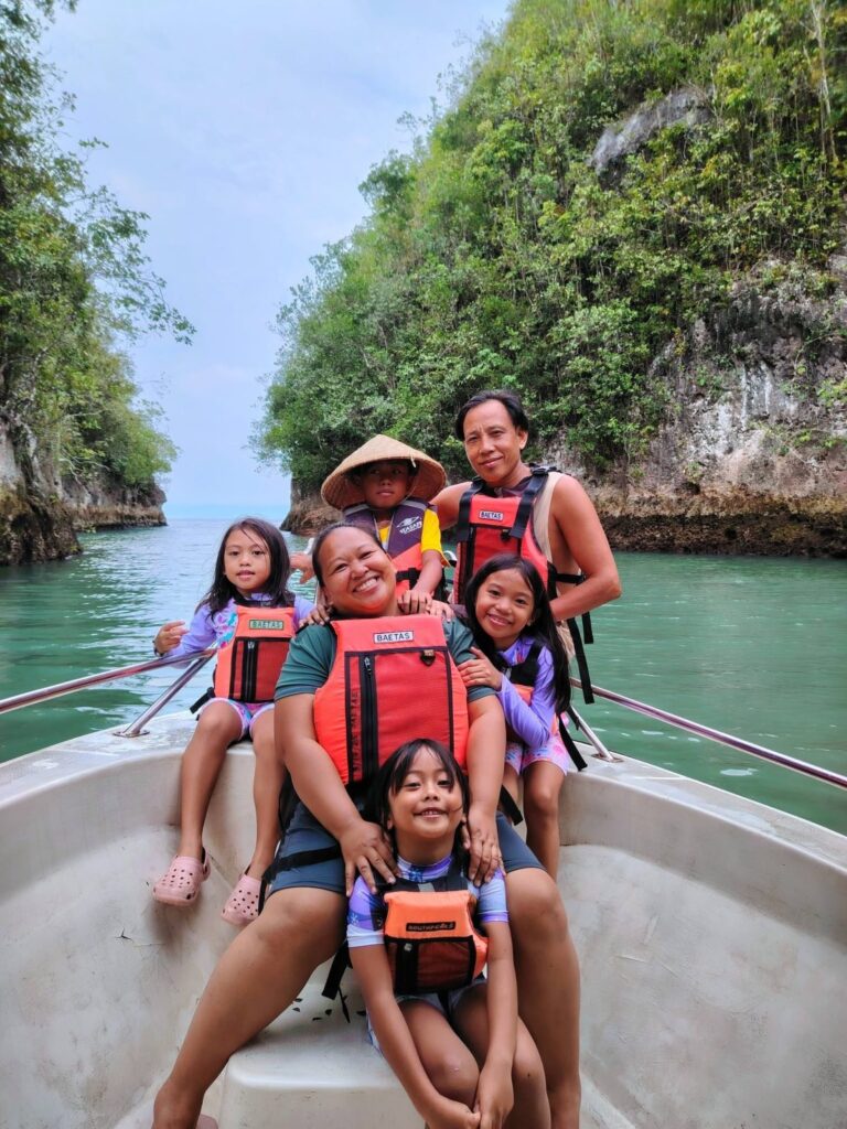 A family in life vests on the tour boat with limestone cliffs behind