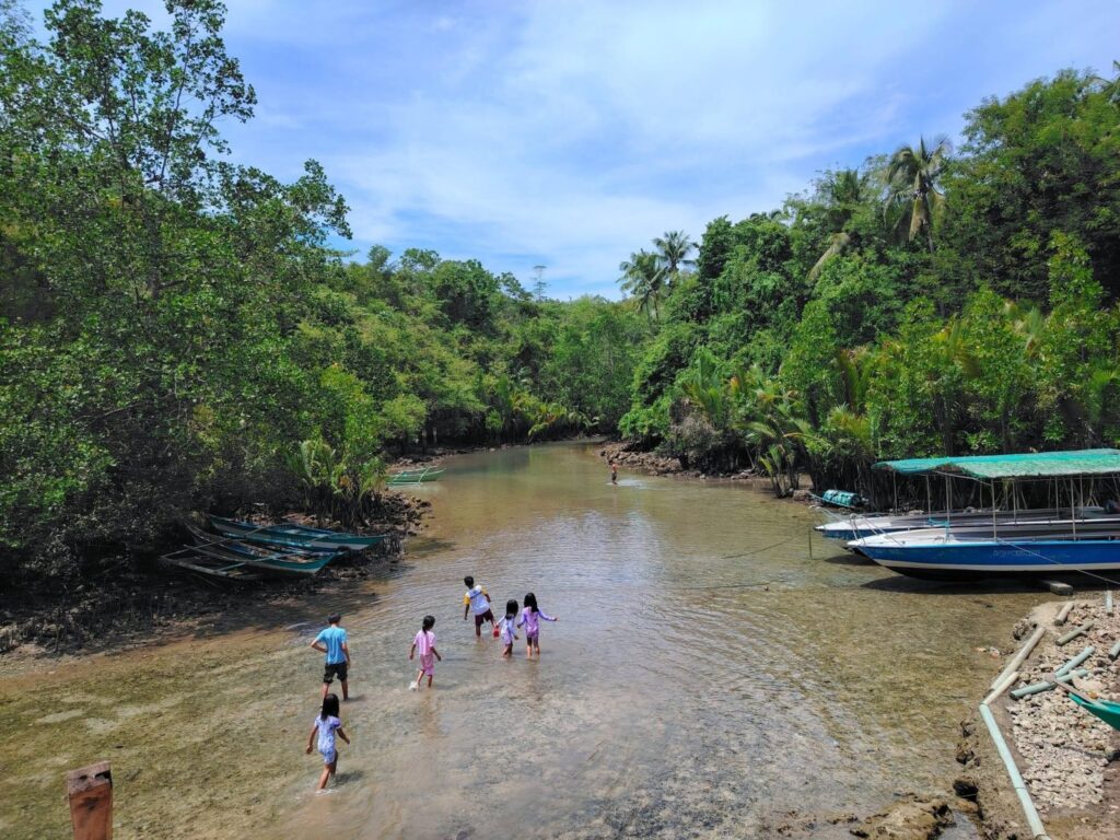 Children wading in the shallow river beside moored tour boats