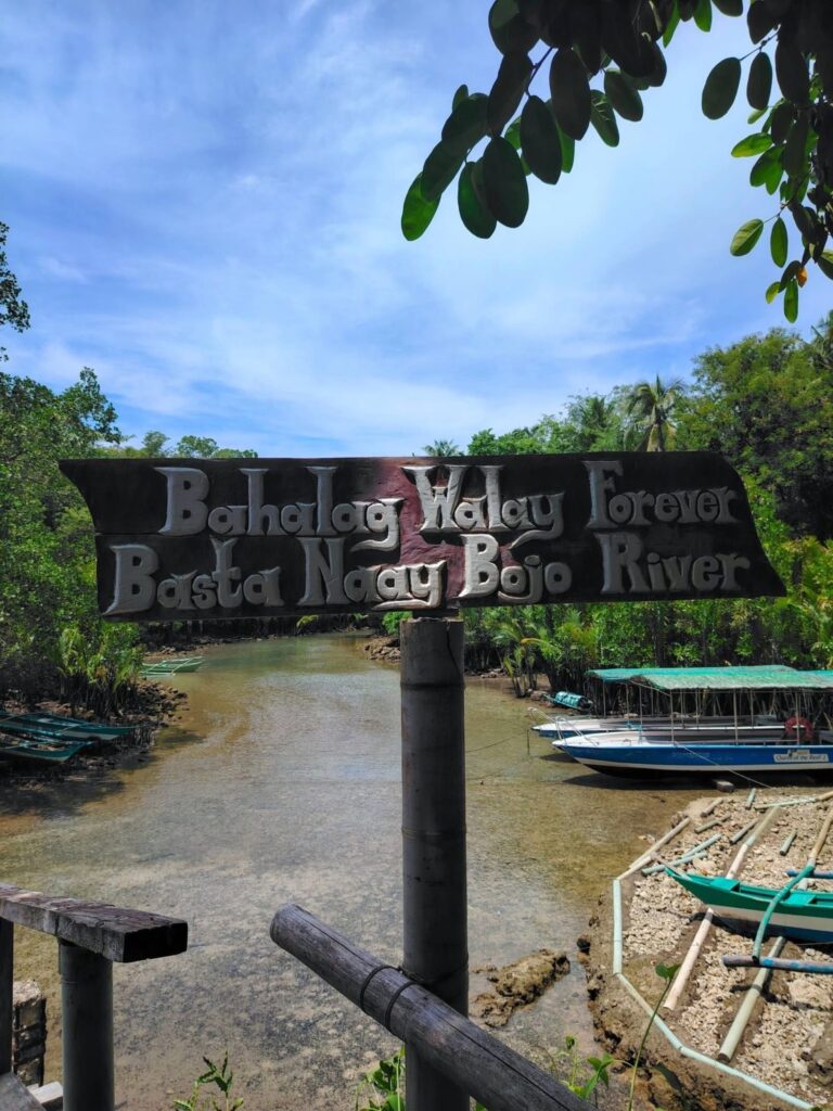 A sign reading Bahalag walay forever, basta naay Bojo River above the boat landing