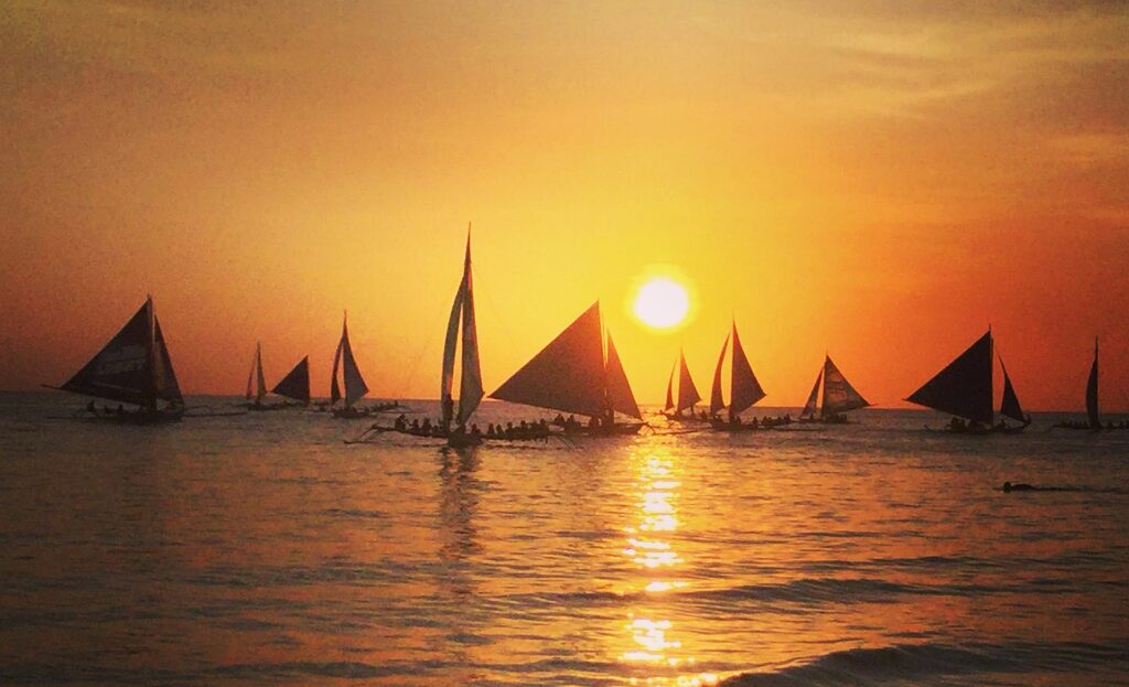 Paraw sailboats silhouetted against the famous Boracay sunset