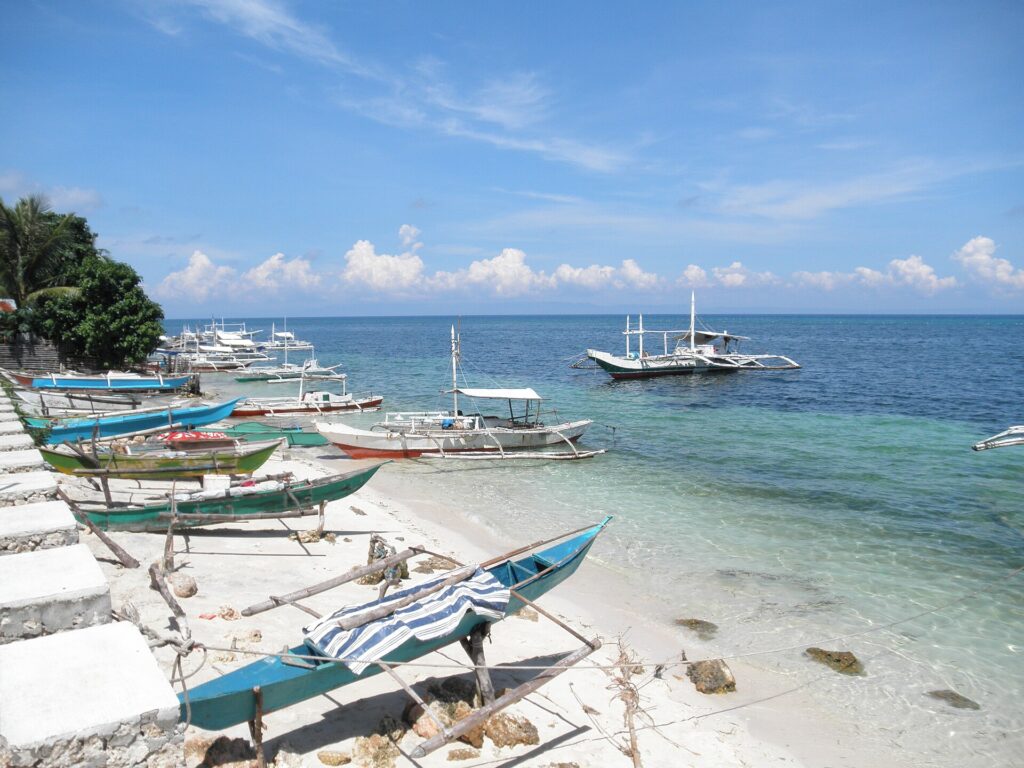 Bangkas lined up on white sand at Santiago Bay