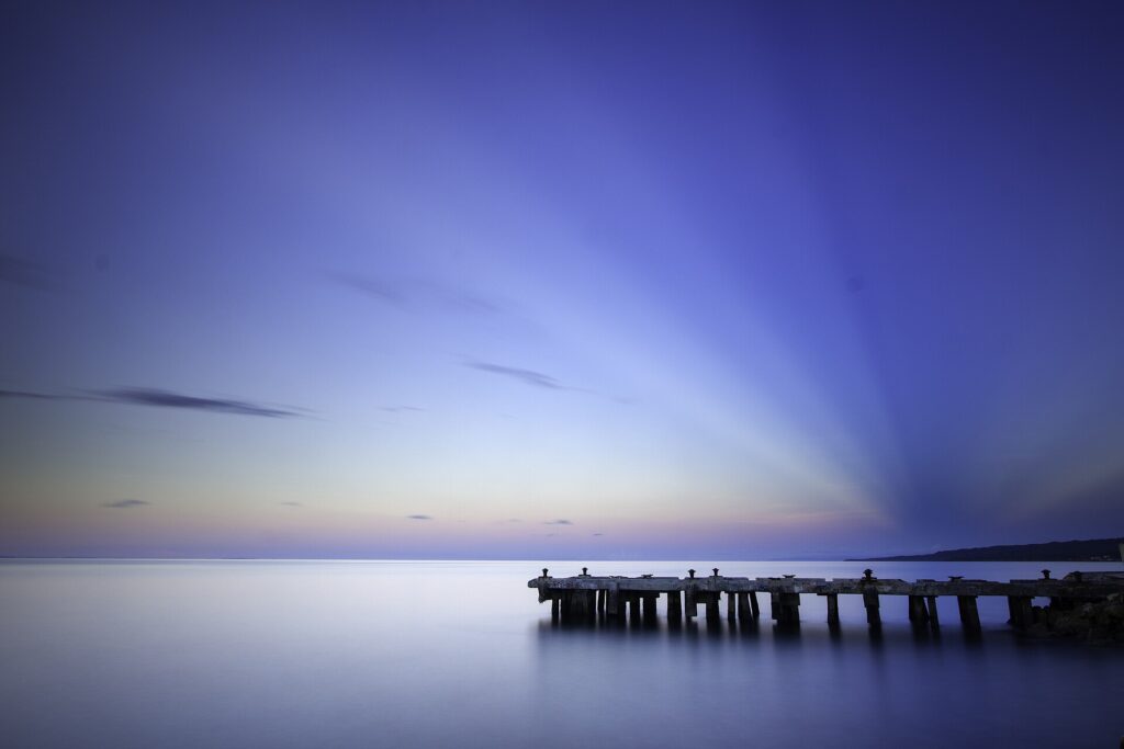 A long pier reaching into still blue water at twilight