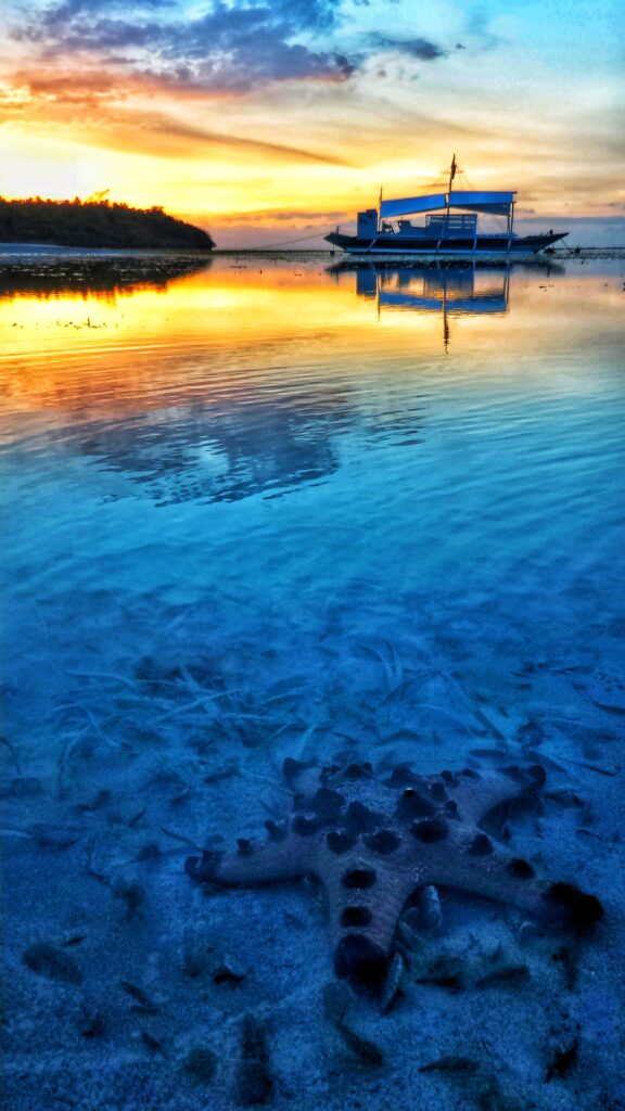 Morning calm in Camotes: a boat on glassy water