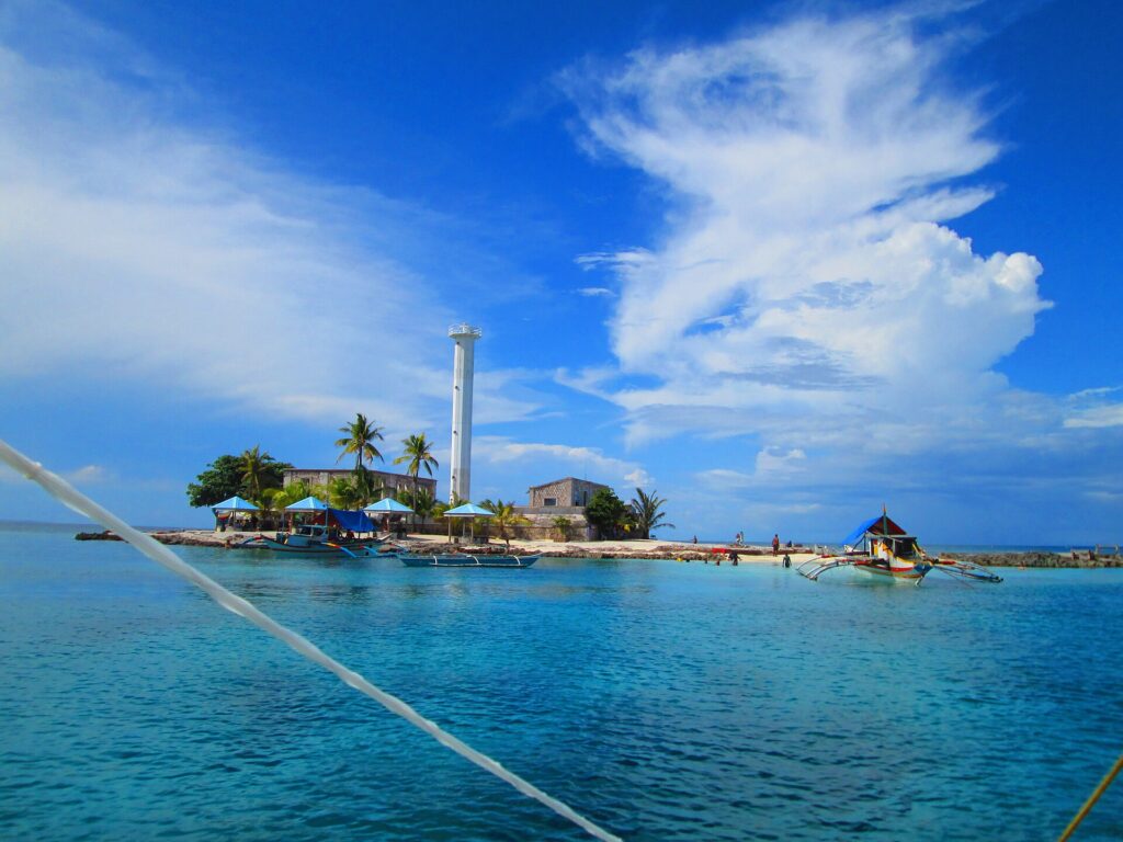 Capitancillo islet with boats and a wide sky
