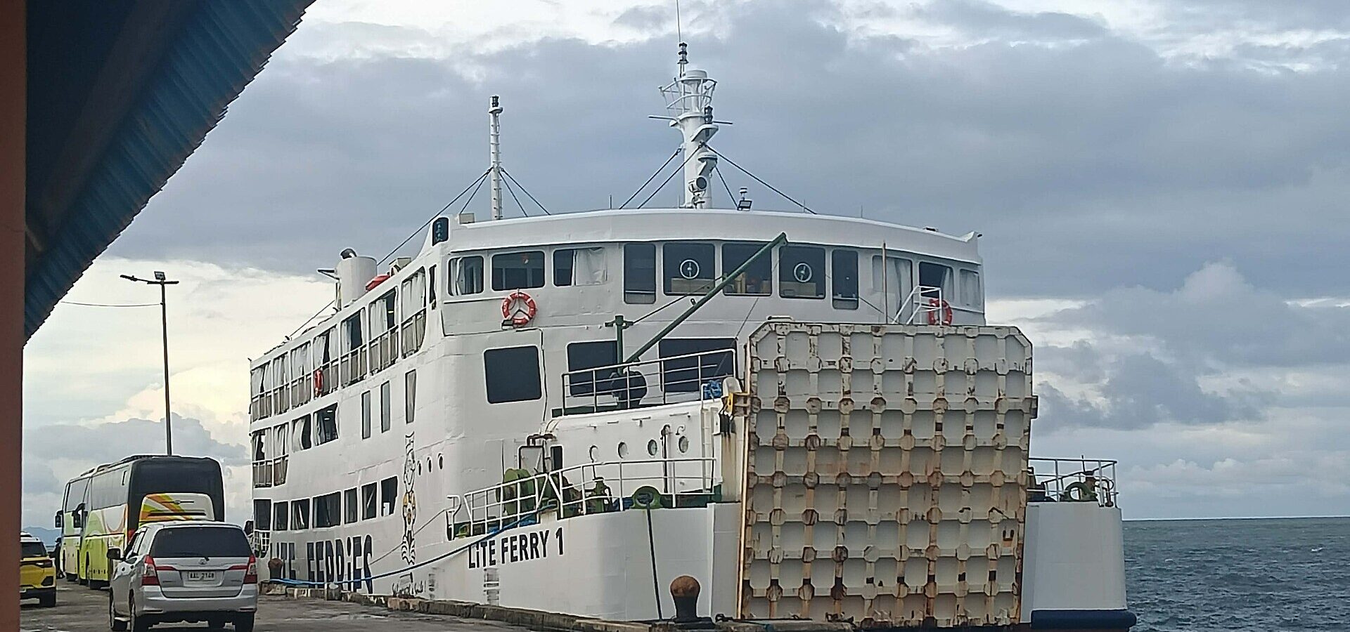 A white passenger ferry docked at a pier in Cebu under a cloudy sky