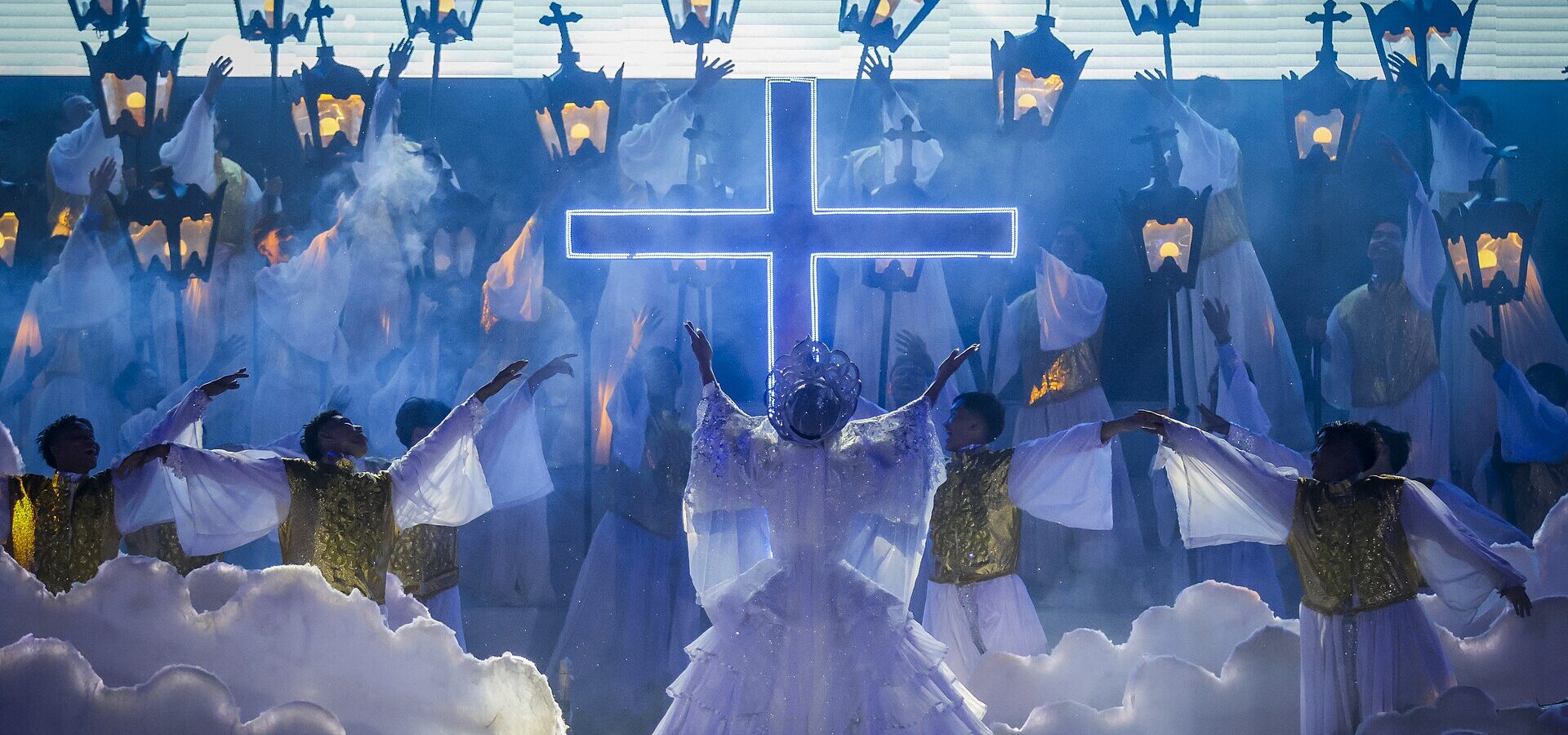 Performers in white and gold before a glowing cross at the Sugat-Kabanhawan Festival in Minglanilla on Easter Sunday