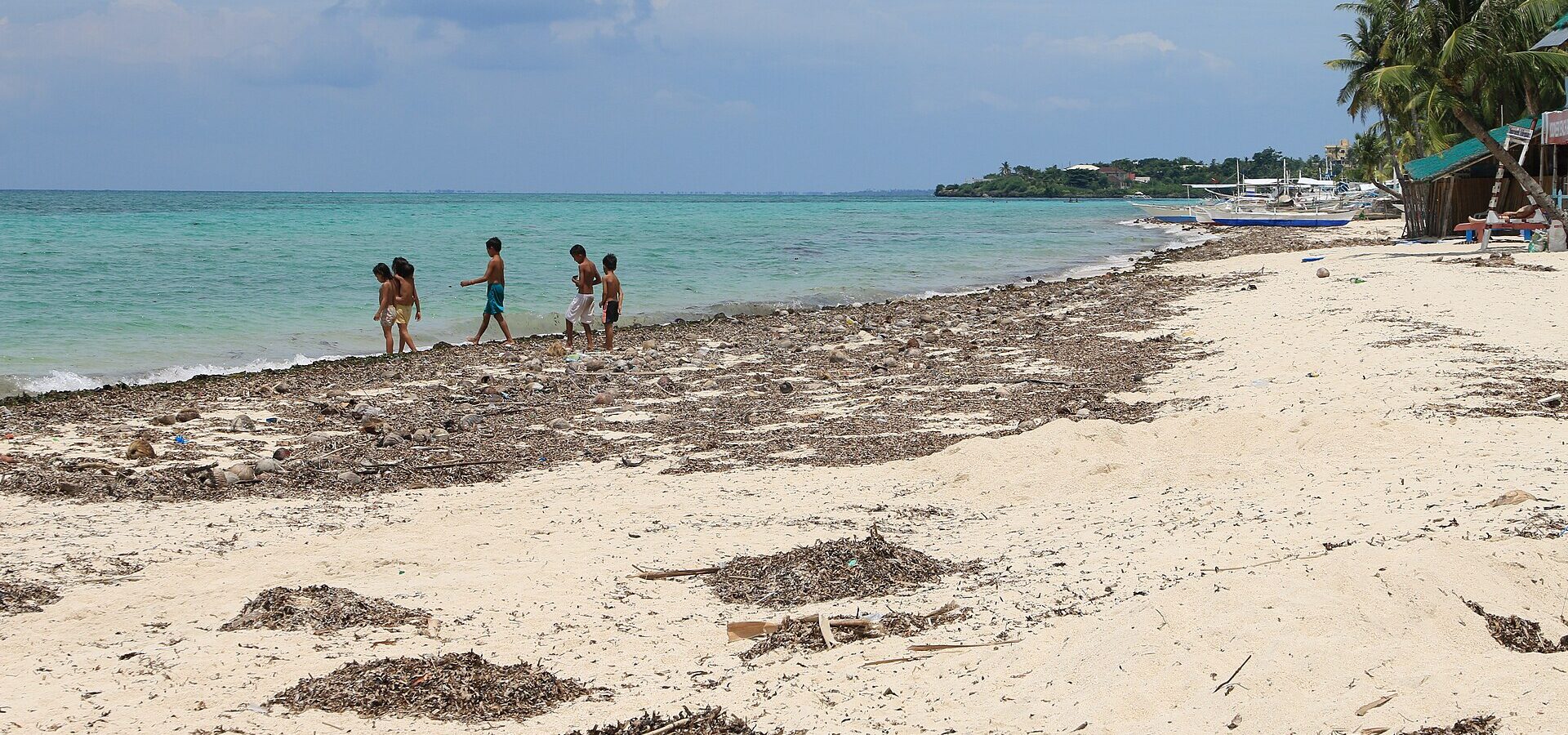 Children walking along a sunny white-sand beach on Bantayan Island