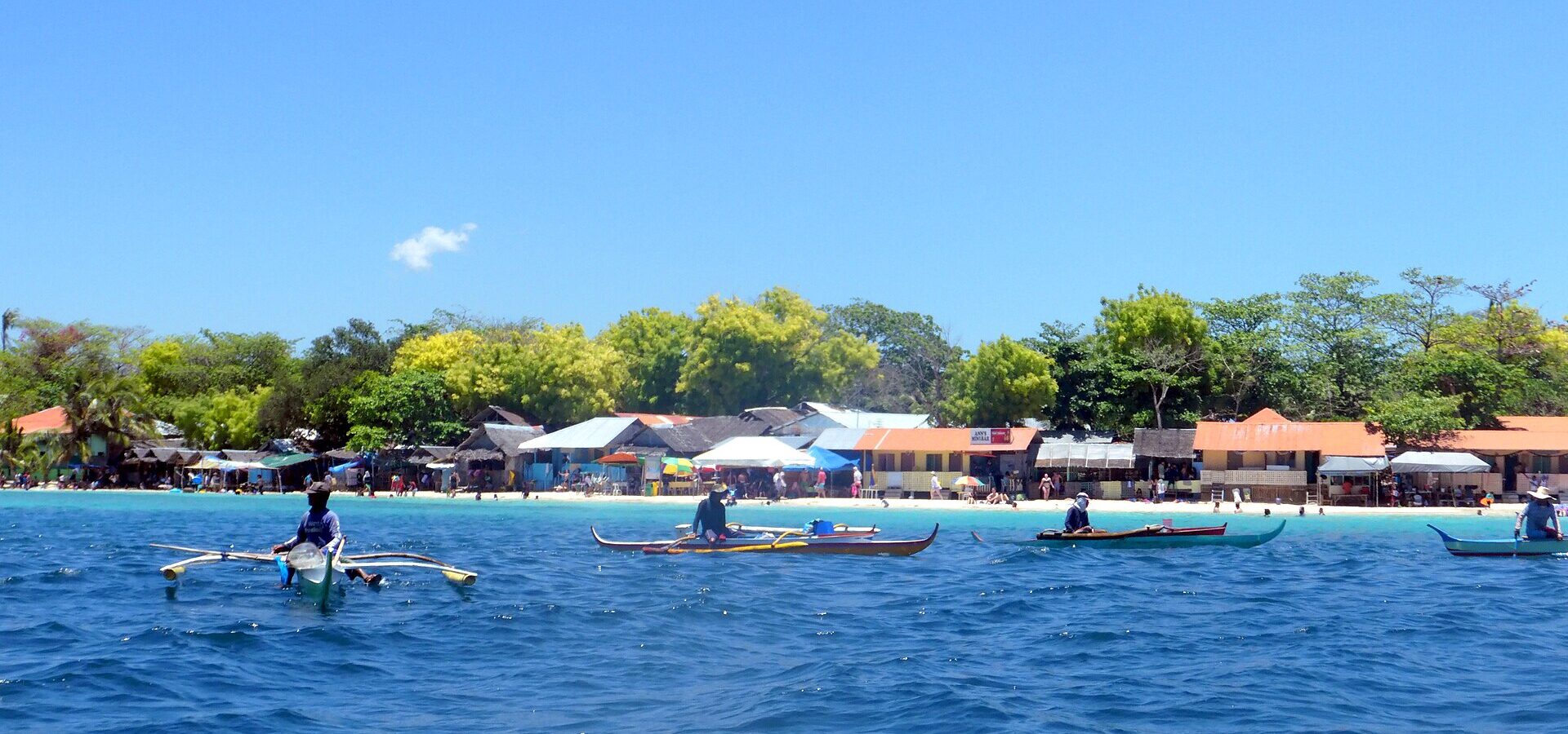 Outrigger boats on blue water off the beach in Moalboal, a classic long day trip from Cebu City