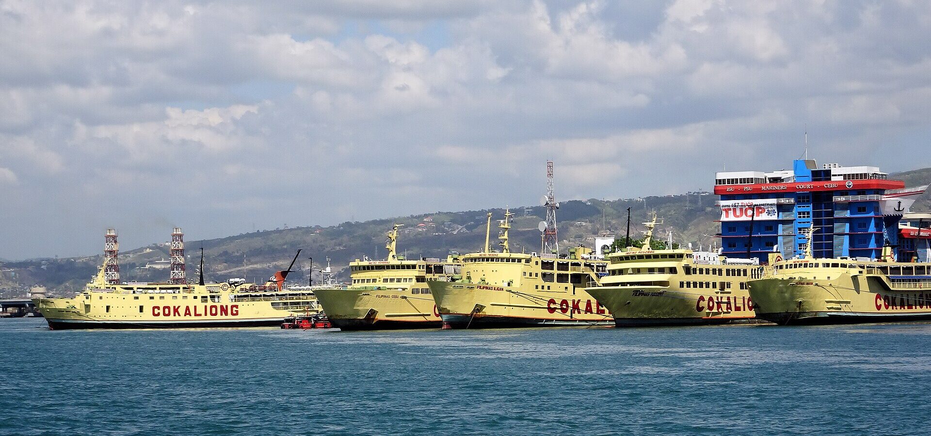 A row of Cokaliong ferries moored at the Port of Cebu, with the city hills behind