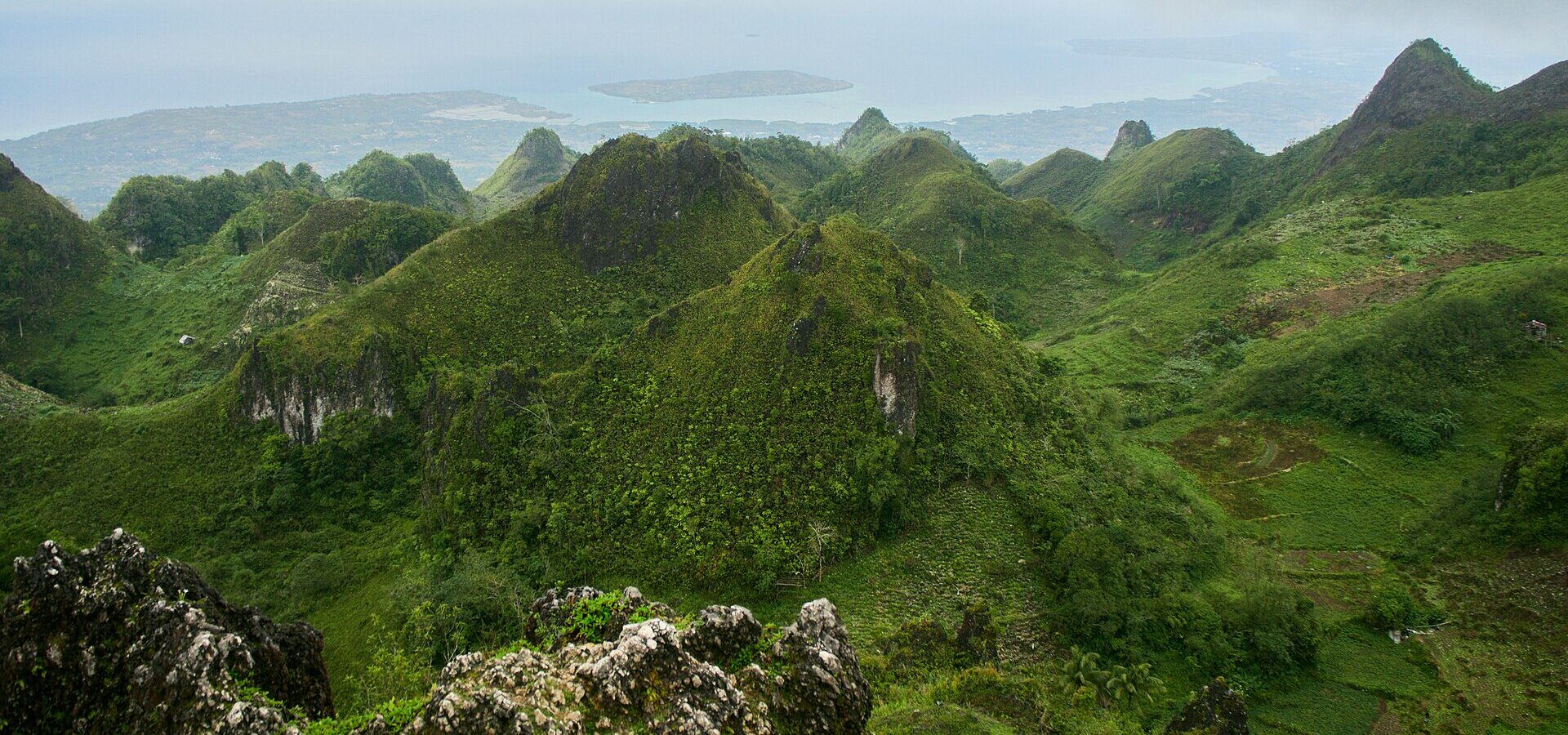 Jagged green karst hills seen from Osmeña Peak in Dalaguete, with the coast and islands in the distance