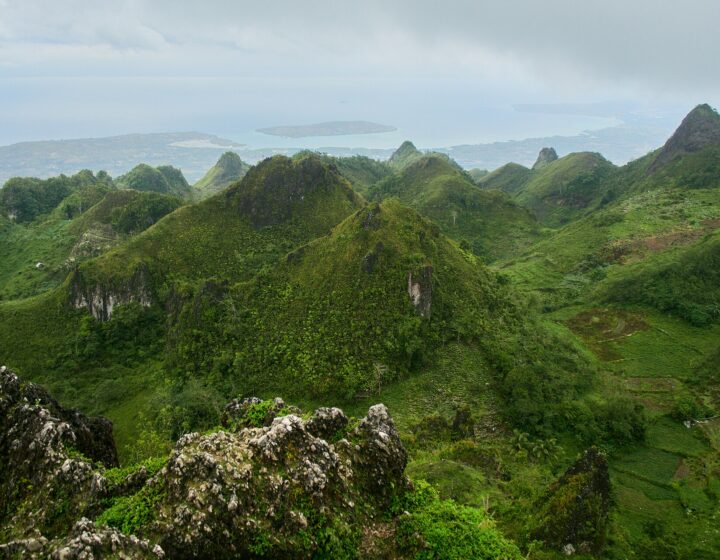 Jagged green karst hills seen from Osmeña Peak in Dalaguete, with the coast and islands in the distance