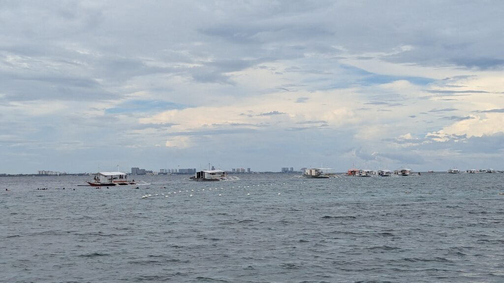 Tour boats moored along a buoy line near the Hilutungan sanctuary