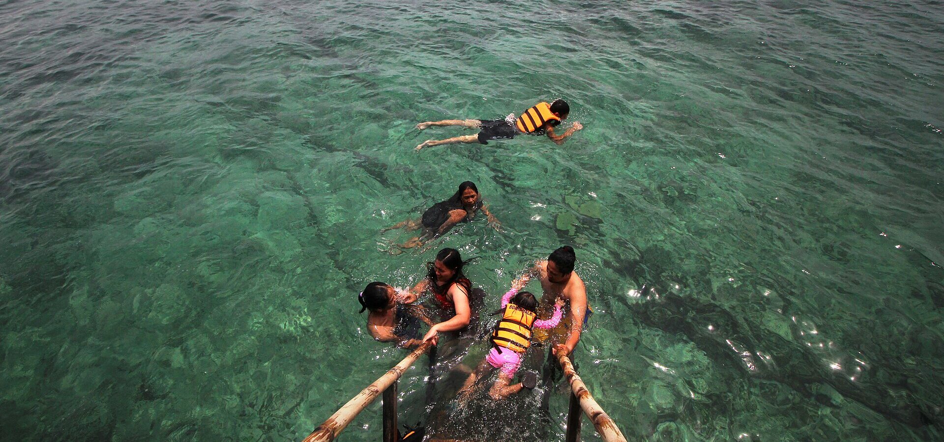 Visitors in life jackets snorkelling from a bangka in the clear water of San Vicente Marine Sanctuary, Olango Island
