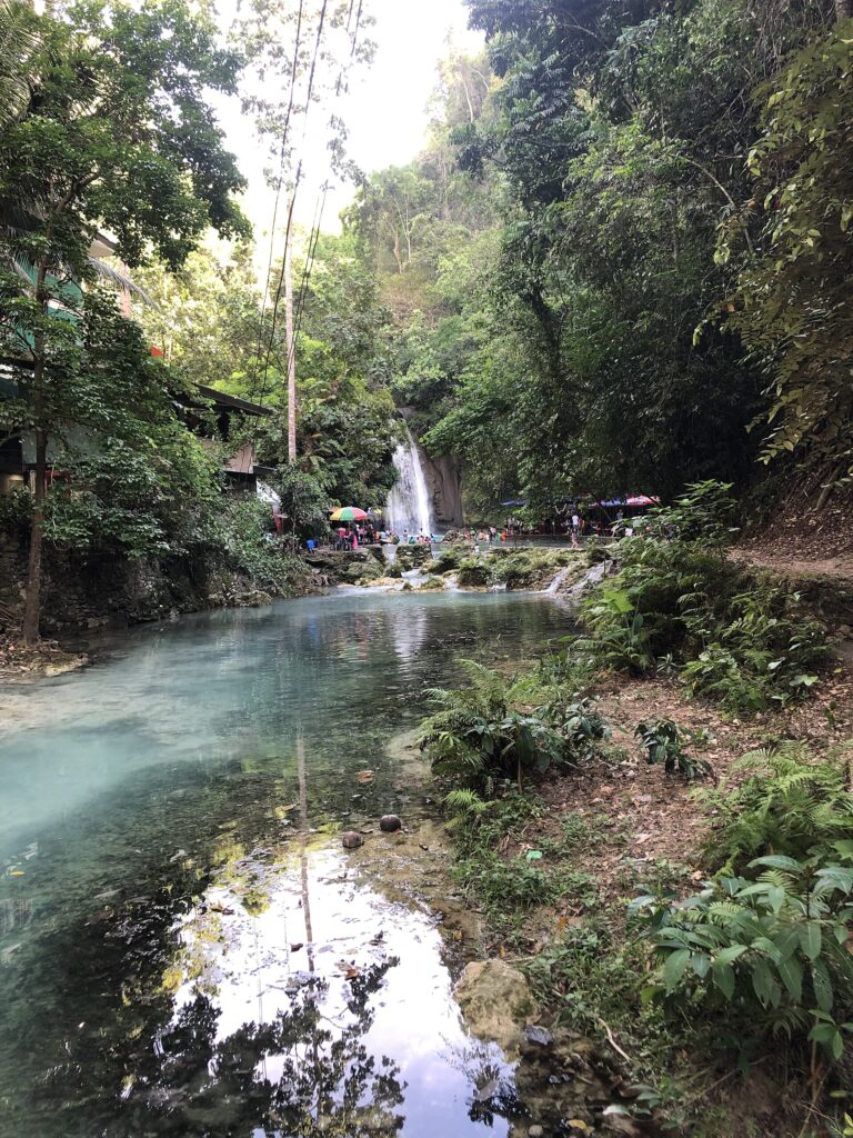 The blue lagoon and jungle below the falls in Matutinao
