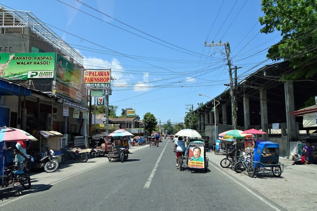 The main street of Badian town with tricycles and shops