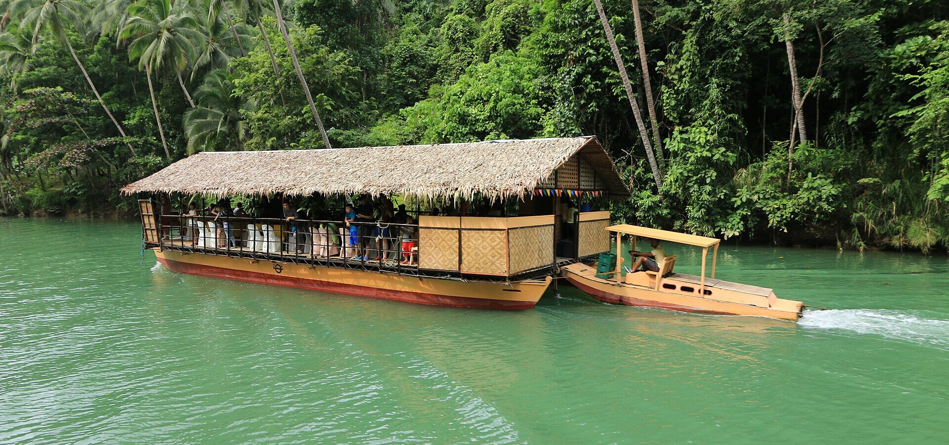 A Loboc River cruise boat on the green river with forest on the banks
