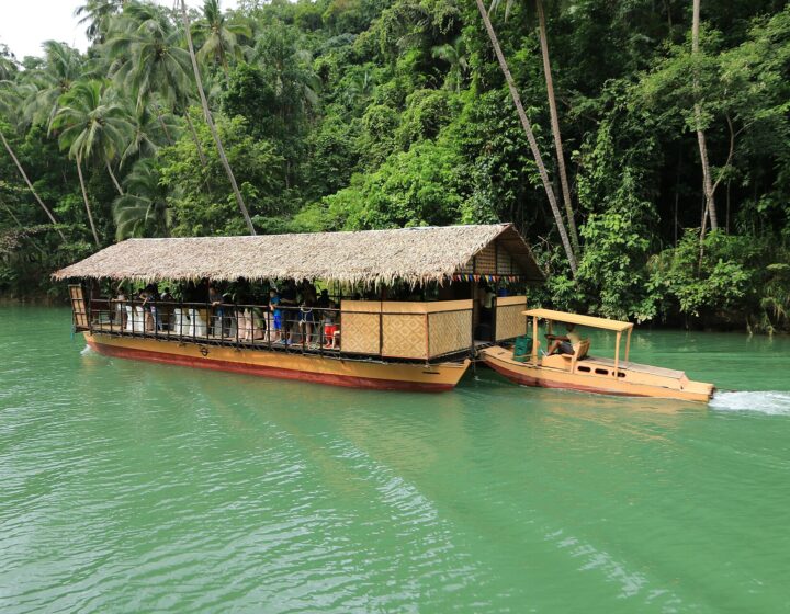 A Loboc River cruise boat on the green river with forest on the banks
