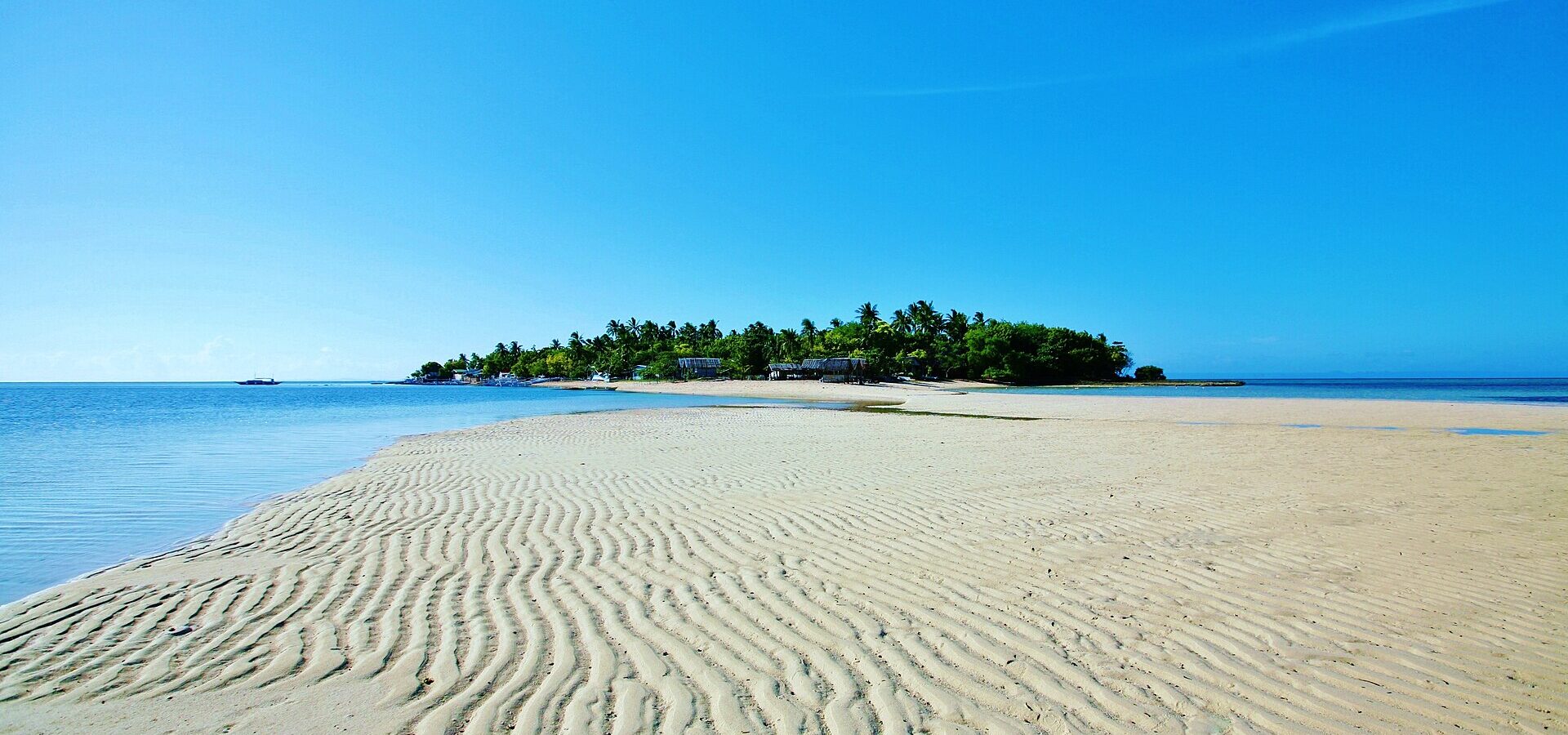 Caohagan Island seen across a rippled white sandbar at low tide, one of the island-hopping stops off Mactan