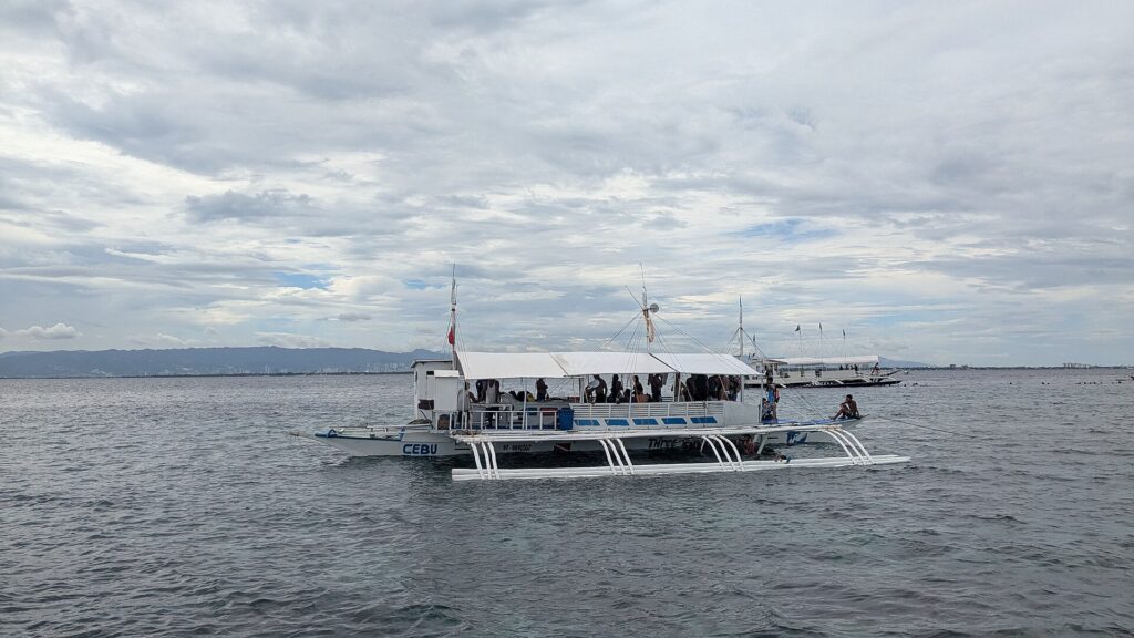 A big outrigger bangka out on the strait, Cebu hills behind