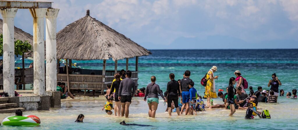 Swimmers in the shallow, clear water at Pandanon Island