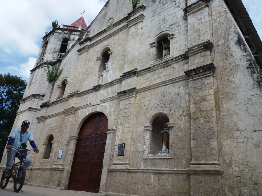 The coral stone facade and bell tower of San Nicolas de Tolentino Church