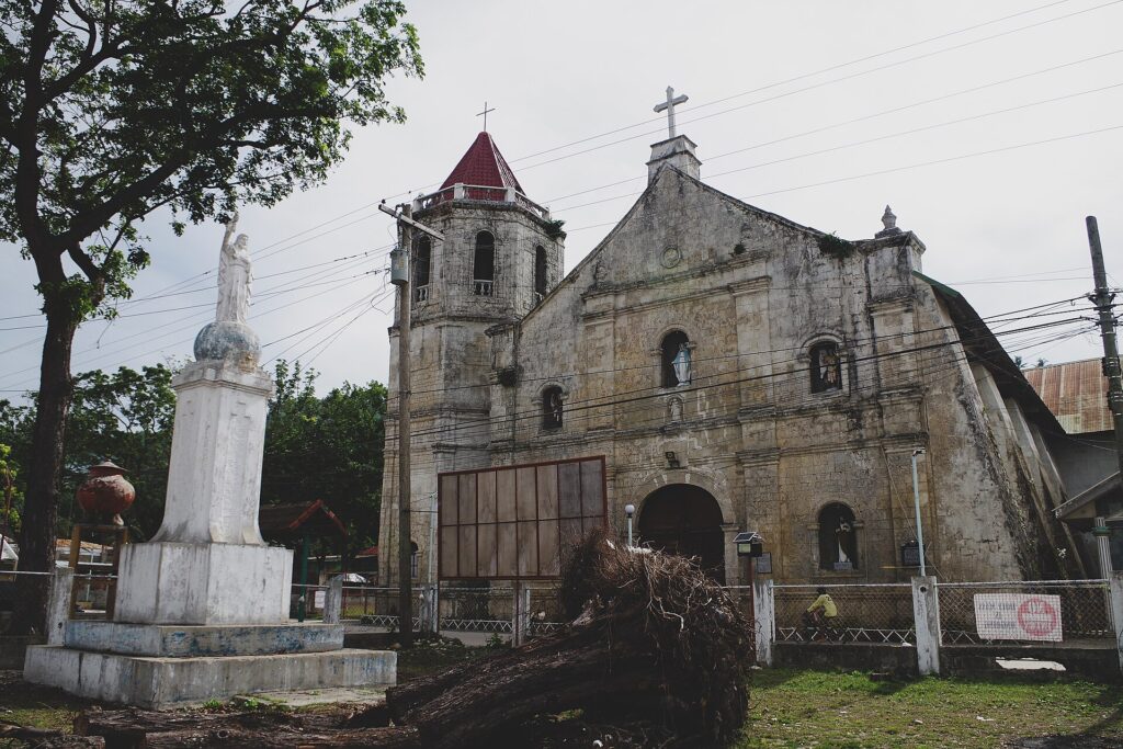 Malabuyoc Church and the plaza monument on a cloudy day
