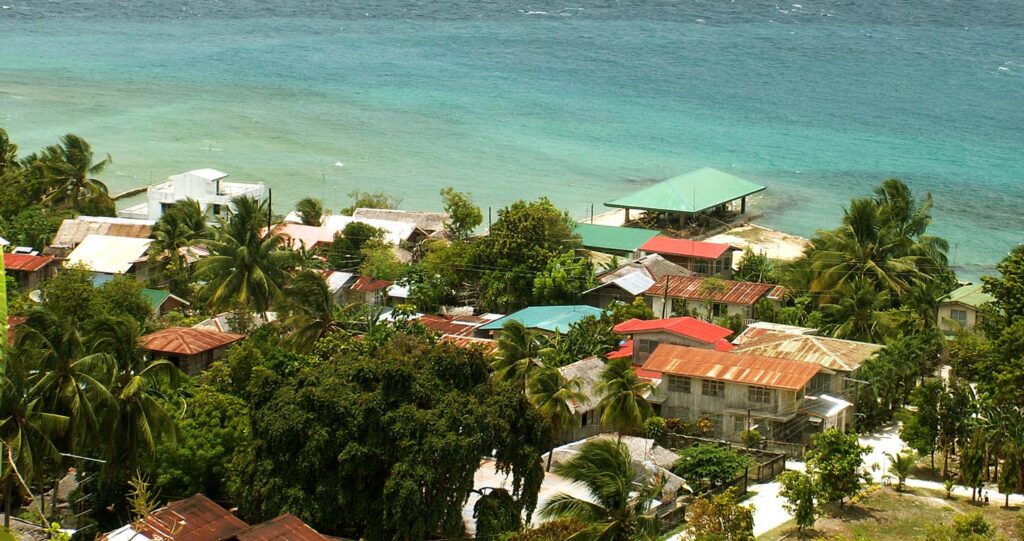 Rooftops, palms and the turquoise sea along the Malabuyoc coast