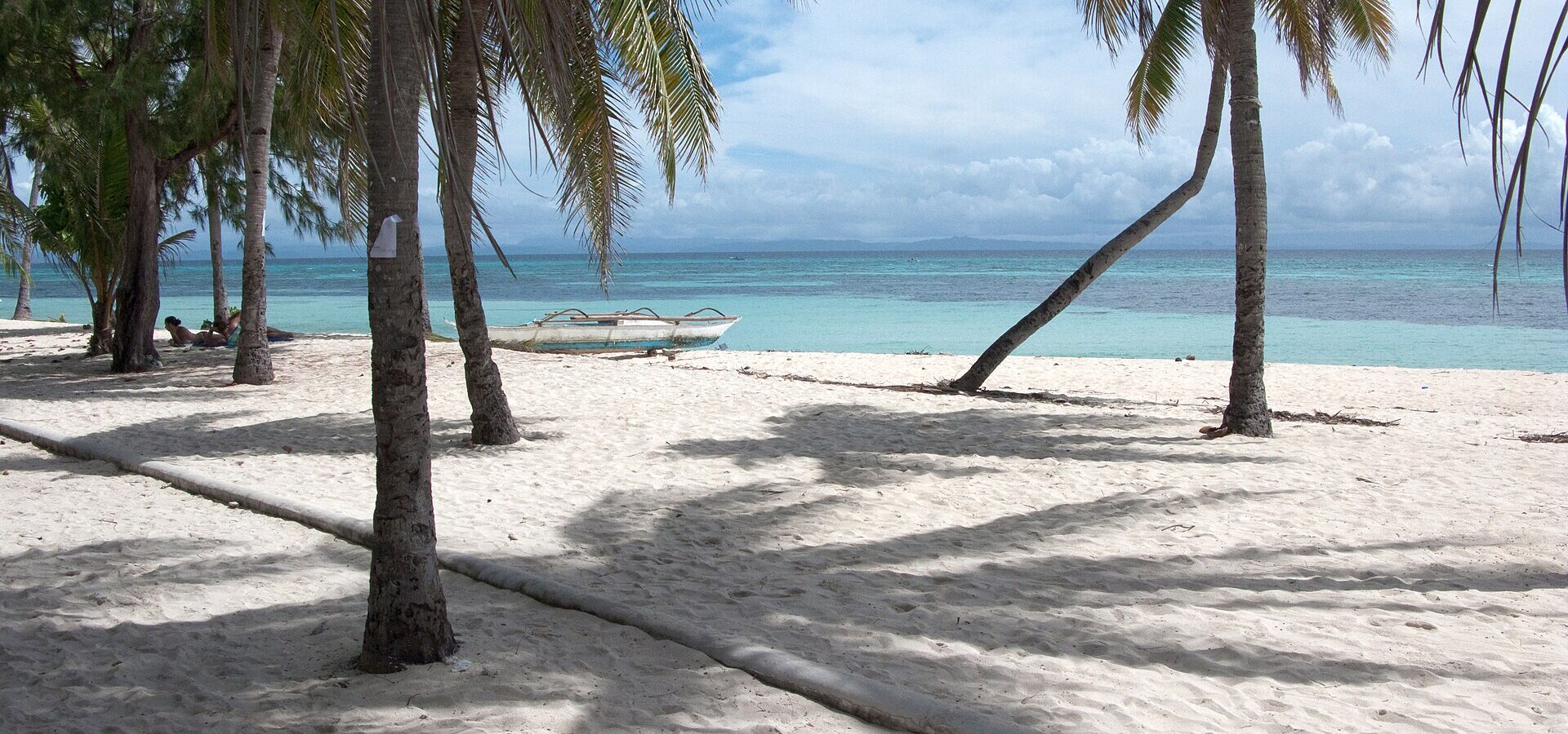 Palm trees on the white sand of Bounty Beach on Malapascua Island, with turquoise water behind
