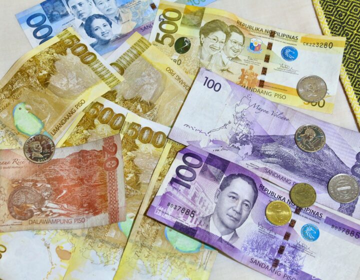 Philippine peso banknotes (₱20, ₱100, ₱500, ₱1,000) and coins spread on a table