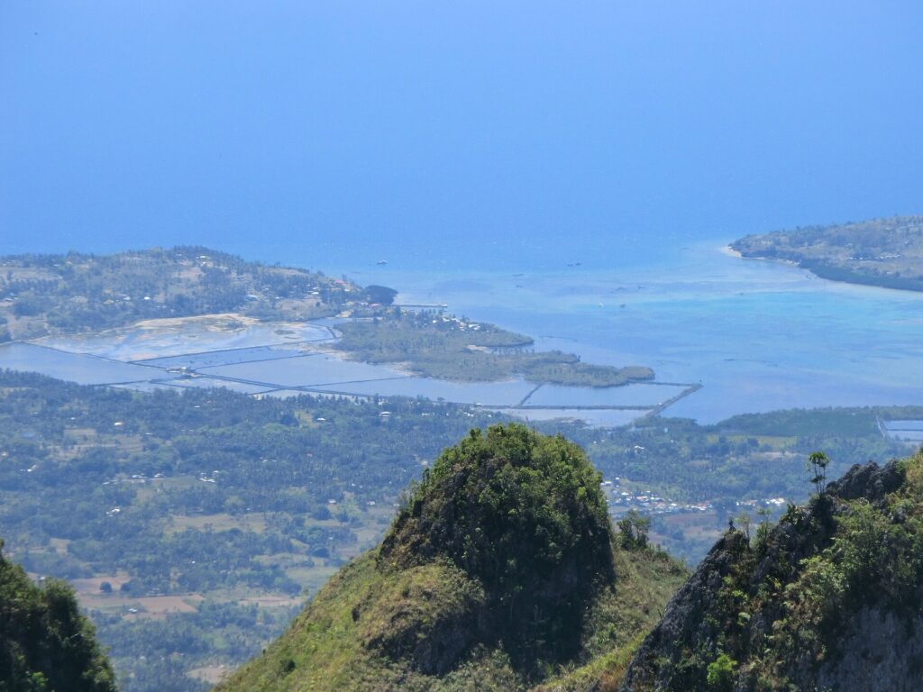 A sharp green peak above the coast and blue sea
