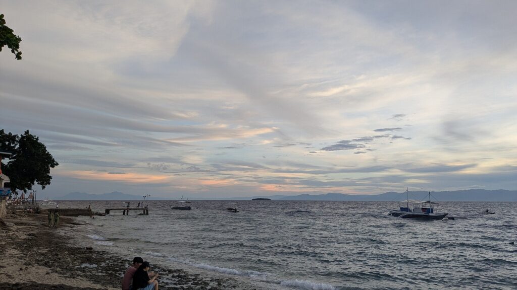 Dusk along the Panagsama shoreline, with a small pier on the left