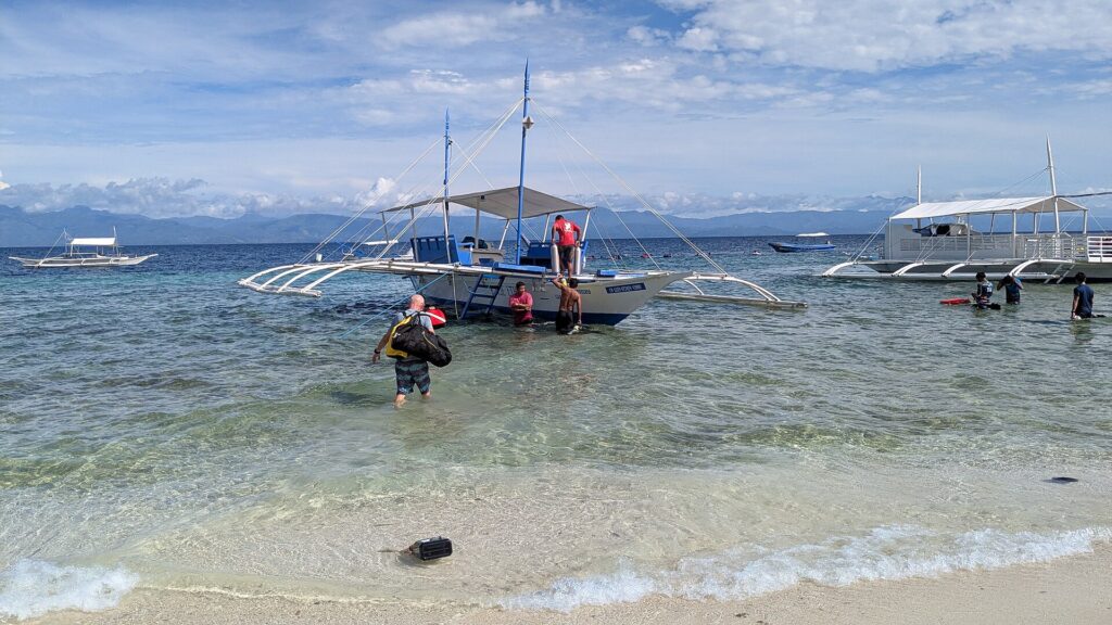 A dive boat loading guests in the shallows