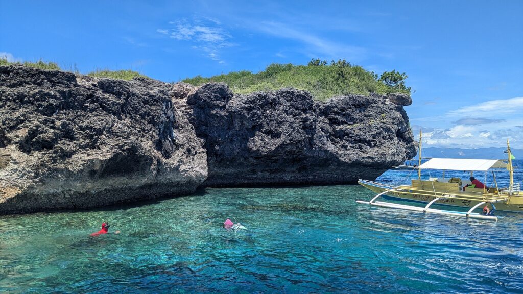 An outrigger bangka waiting by the cliffs at Pescador Island