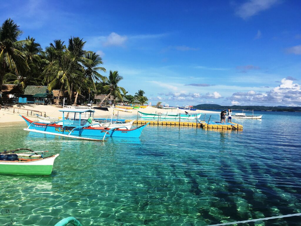 Island-hopping bancas moored in clear turquoise water off Siargao