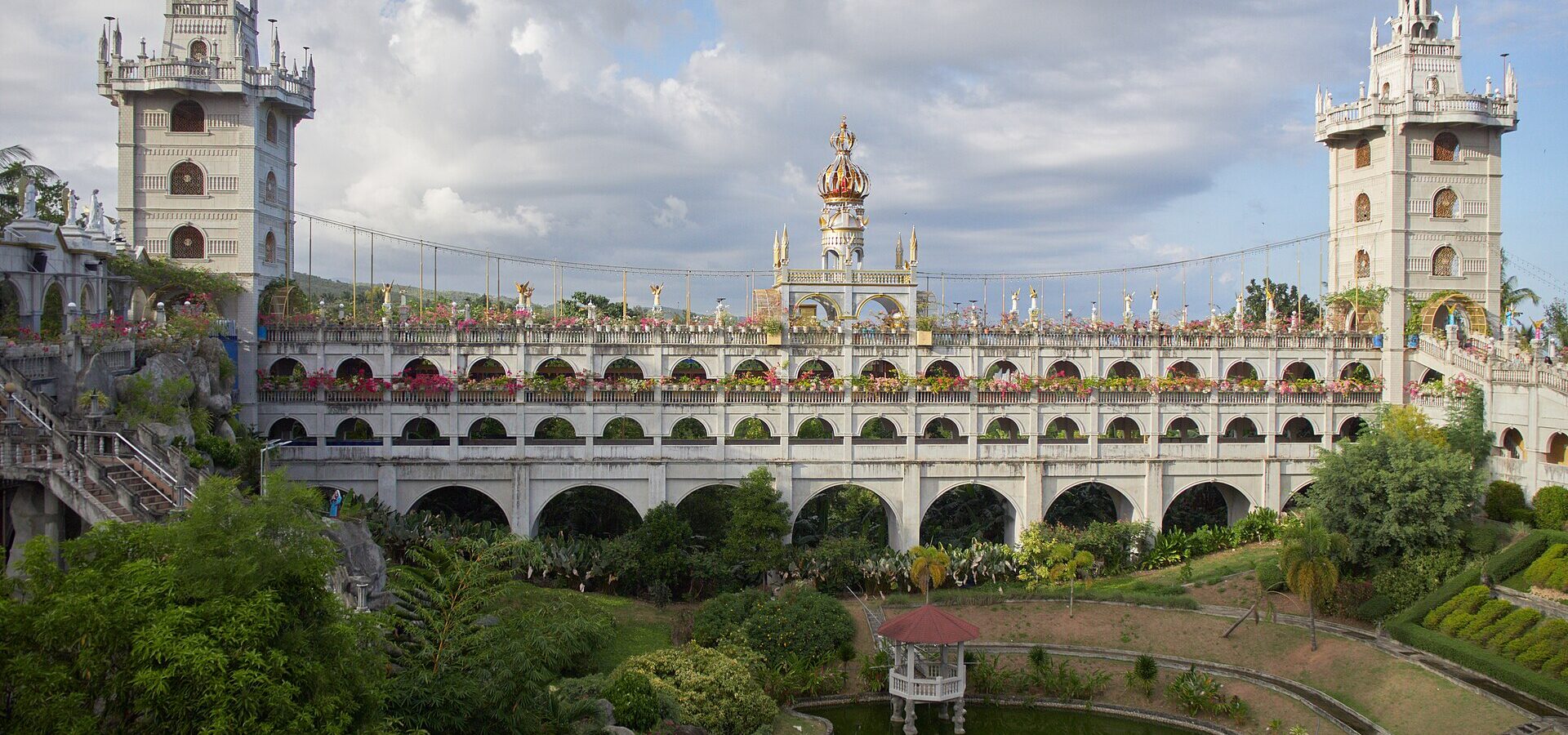 The white towers and arched galleries of the Simala Shrine above its gardens and pond
