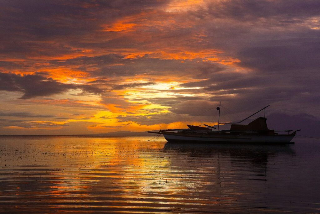 Sunset and an outrigger boat on the calm sea off San Juan