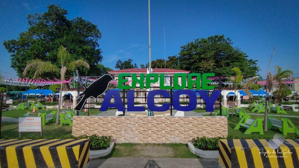 The Explore Alcoy sign in the town plaza, with the siloy bird