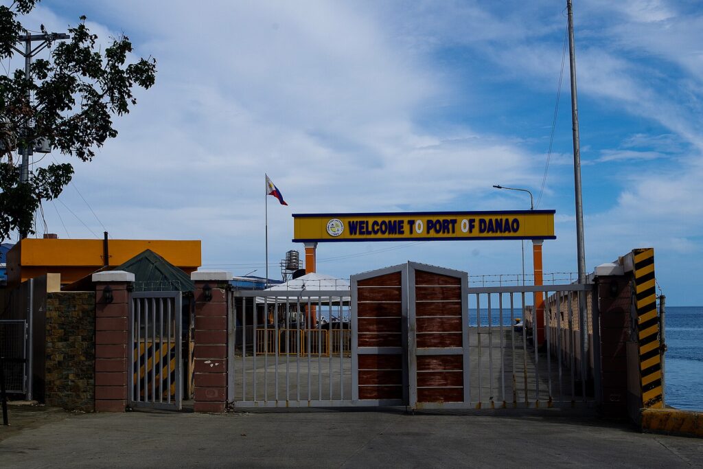 The Welcome to Port of Danao gate beside the pier with blue sky above