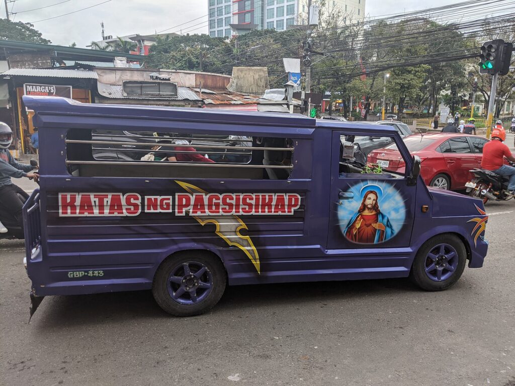 A purple van-style modern jeepney with painted decoration in Cebu City