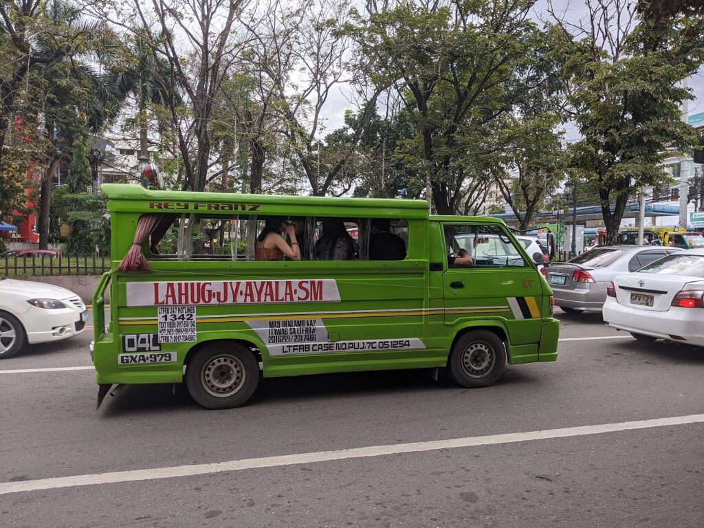 A green jeepney with the route Lahug JY Ayala SM painted on its side, in Cebu City traffic
