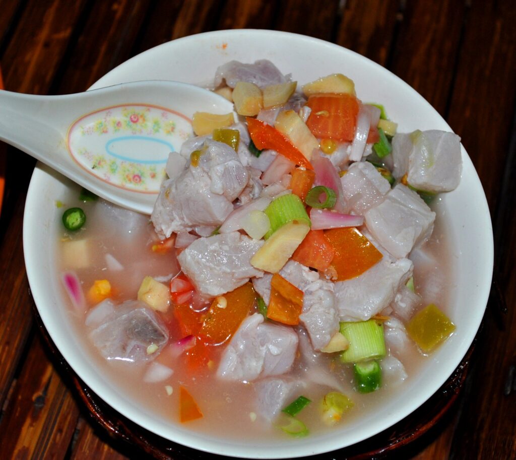 A bowl of kinilaw, raw fish cured in vinegar and citrus with onion and chili, served with a spoon in Carcar, Cebu