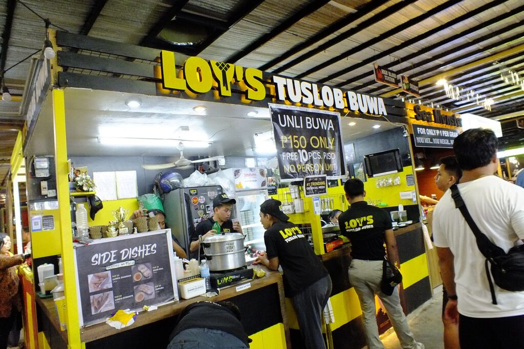 A yellow tuslob buwa food stall with a menu board at the Carbon Market in Cebu City